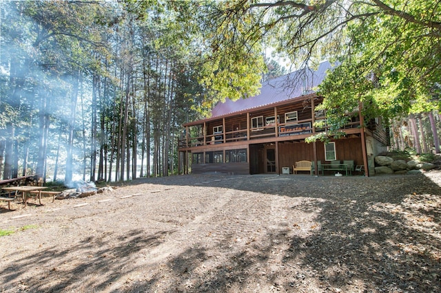 rear view of house with dirt driveway, metal roof, and a wooden deck