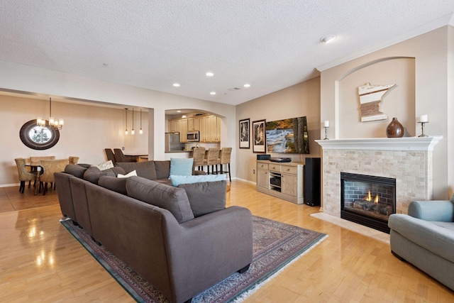 living room with a fireplace, light wood-style flooring, and a textured ceiling