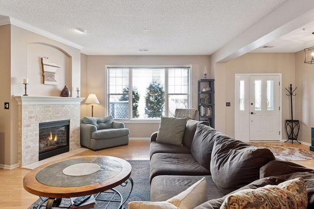 living area with baseboards, a textured ceiling, a tile fireplace, and light wood-style floors