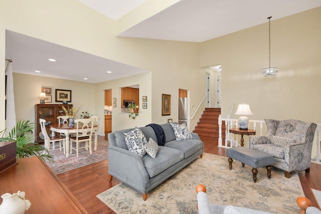 living area featuring vaulted ceiling, wood finished floors, stairway, and recessed lighting