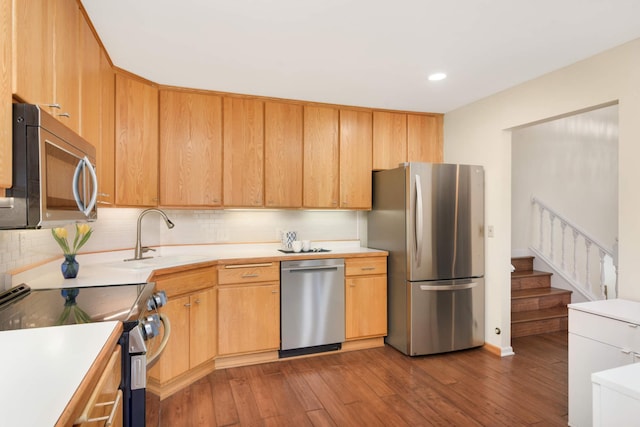 kitchen featuring a sink, hardwood / wood-style floors, light countertops, appliances with stainless steel finishes, and decorative backsplash