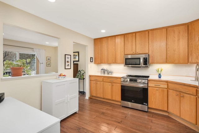 kitchen with stainless steel appliances, recessed lighting, wood-type flooring, light countertops, and tasteful backsplash