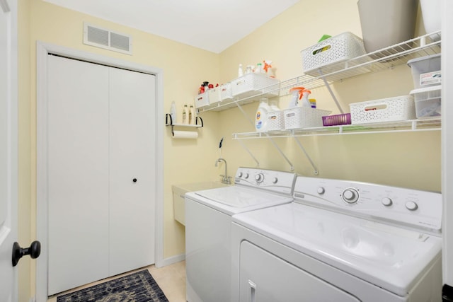 washroom with a sink, independent washer and dryer, laundry area, visible vents, and light tile patterned floors