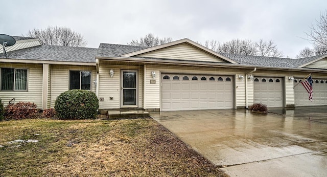 ranch-style house featuring a garage, driveway, and roof with shingles