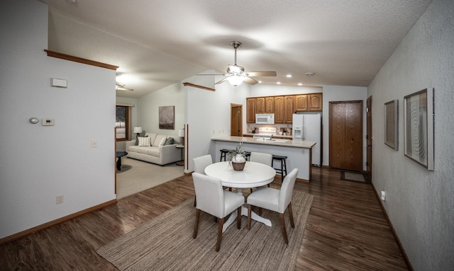 dining space featuring baseboards, ceiling fan, dark wood-style flooring, vaulted ceiling, and a textured ceiling