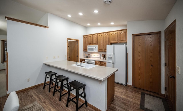 kitchen featuring dark wood-style flooring, white appliances, vaulted ceiling, and a kitchen bar