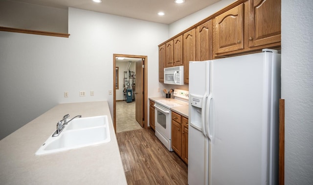 kitchen featuring recessed lighting, white appliances, a sink, light countertops, and dark wood-style floors