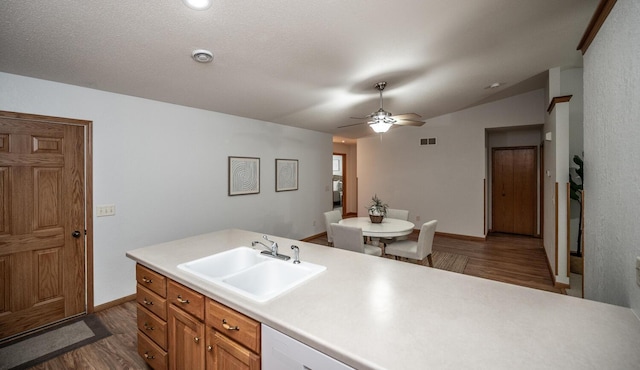 kitchen featuring lofted ceiling, a sink, visible vents, light countertops, and dark wood-style floors