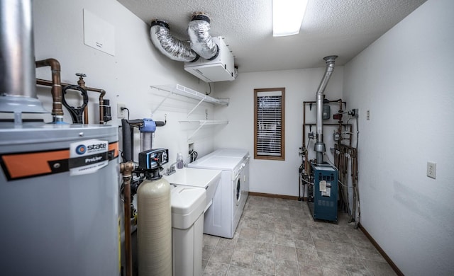 washroom featuring a textured ceiling, laundry area, washing machine and clothes dryer, and baseboards