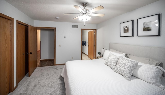 bedroom featuring a ceiling fan, baseboards, visible vents, and two closets