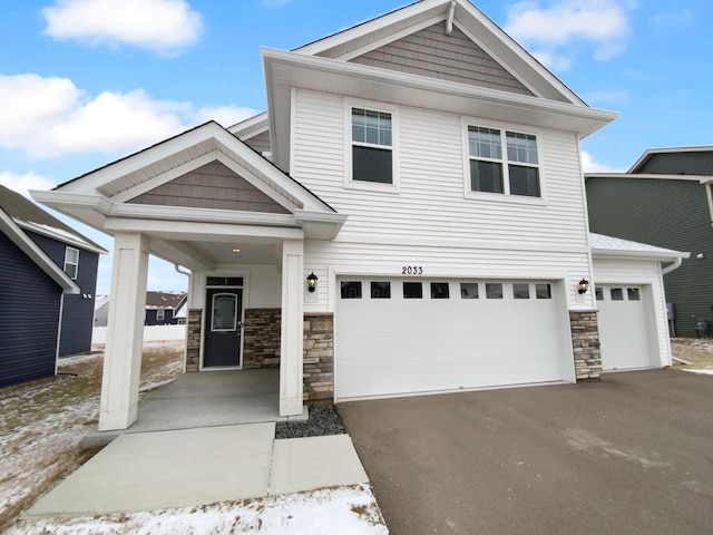 view of front of property featuring stone siding, driveway, and an attached garage