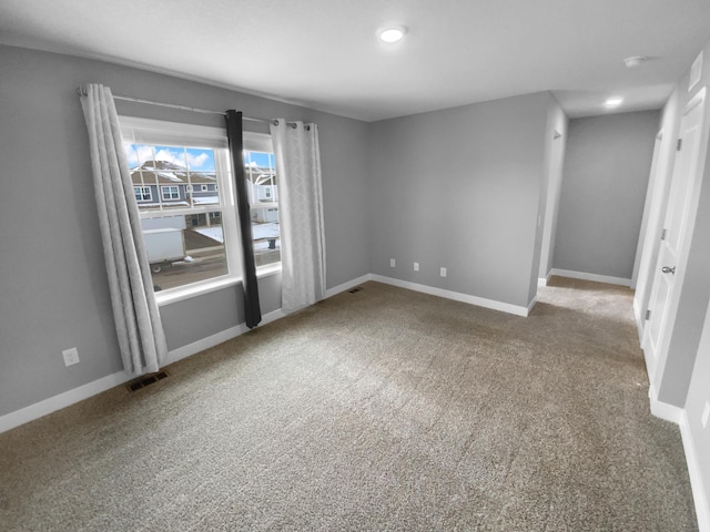 spare room featuring carpet flooring, visible vents, and baseboards