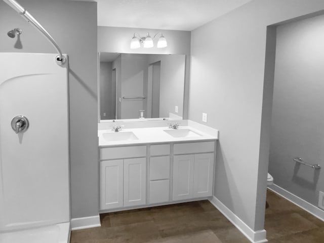 full bathroom featuring baseboards, walk in shower, and a sink