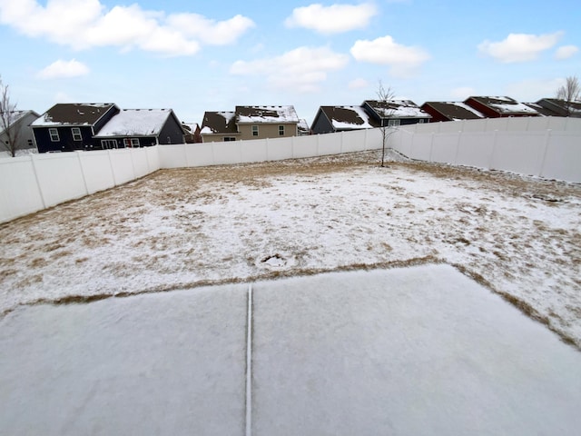 snowy yard with a fenced backyard and a residential view