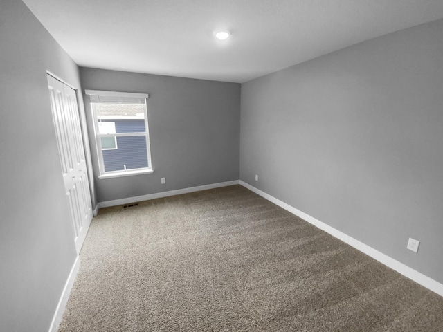 carpeted empty room featuring baseboards and visible vents