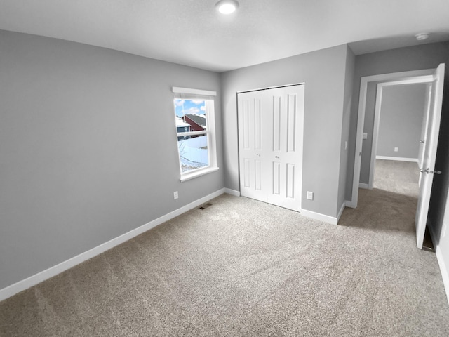 unfurnished bedroom featuring carpet floors, visible vents, baseboards, and a closet