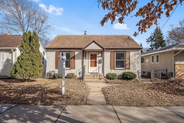 bungalow-style home featuring fence and stucco siding