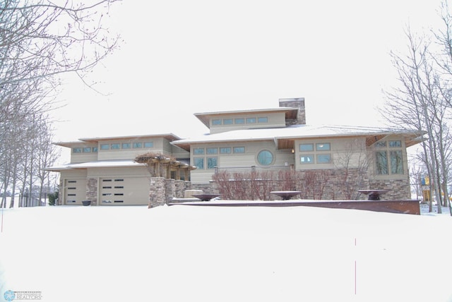 prairie-style house featuring an attached garage and stone siding