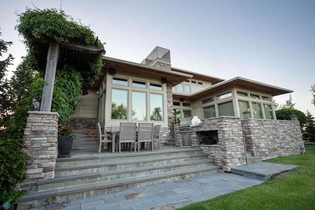 back of house featuring stone siding and a chimney