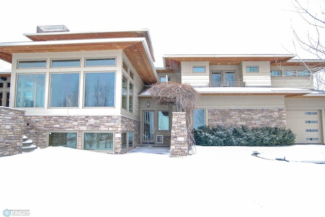 view of front facade with stone siding, a balcony, and central AC unit