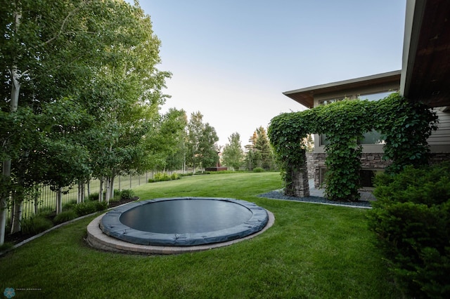 view of yard with a trampoline and fence