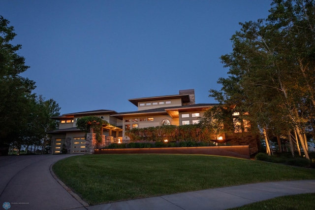 view of front of property with a garage, a front yard, stone siding, and driveway
