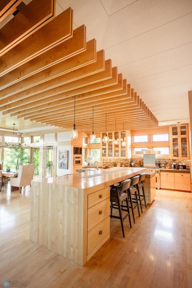 kitchen featuring butcher block countertops, light wood-type flooring, light brown cabinets, and a kitchen breakfast bar