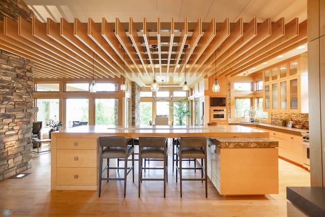kitchen featuring glass insert cabinets, light wood-style floors, appliances with stainless steel finishes, and decorative backsplash