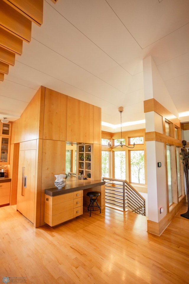 kitchen with dark countertops, an inviting chandelier, light wood-style flooring, and pendant lighting