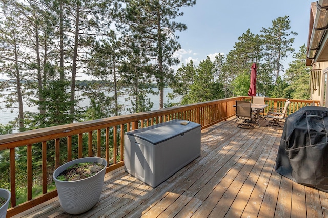 deck with outdoor dining area, a water view, and grilling area