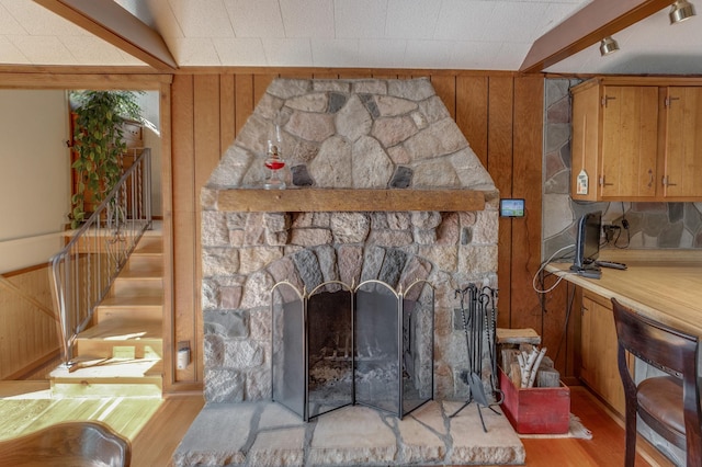 interior details with wood walls, a stone fireplace, and wood finished floors