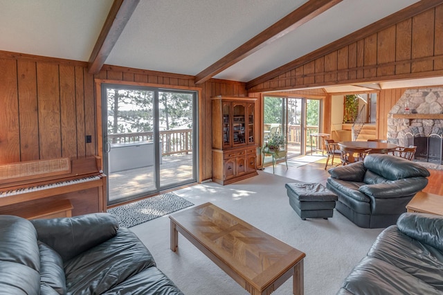 living area with vaulted ceiling with beams, wooden walls, a fireplace, and light colored carpet