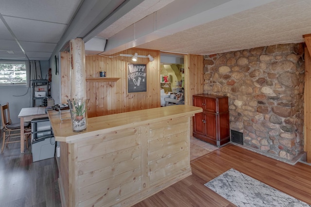 bar featuring wood walls, light wood-style flooring, and a drop ceiling