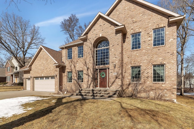 traditional-style house featuring driveway, a front yard, a garage, and brick siding