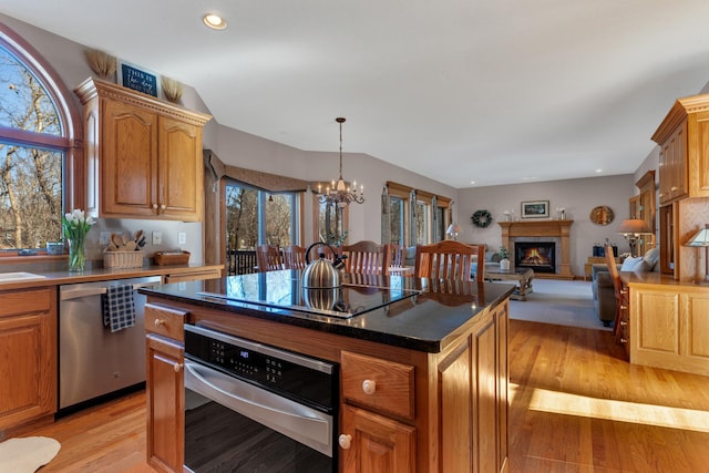 617 17th St N, Sartell, MN 56377 - kitchen featuring appliances with stainless steel finishes, light wood-style flooring, a chandelier, a lit fireplace, and a kitchen island