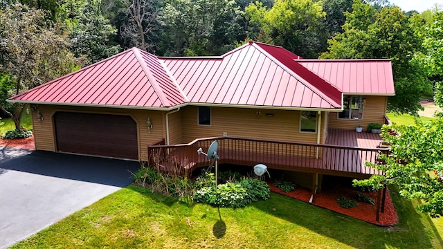 view of front of home with aphalt driveway, a standing seam roof, an attached garage, and a front lawn