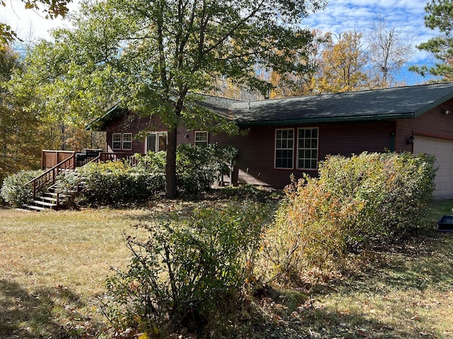 exterior space featuring a garage, a deck, and a yard