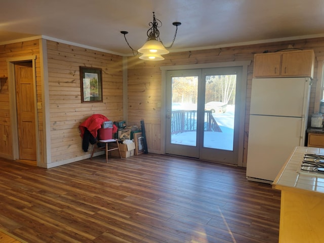 unfurnished dining area with dark wood-style floors, ornamental molding, and wooden walls