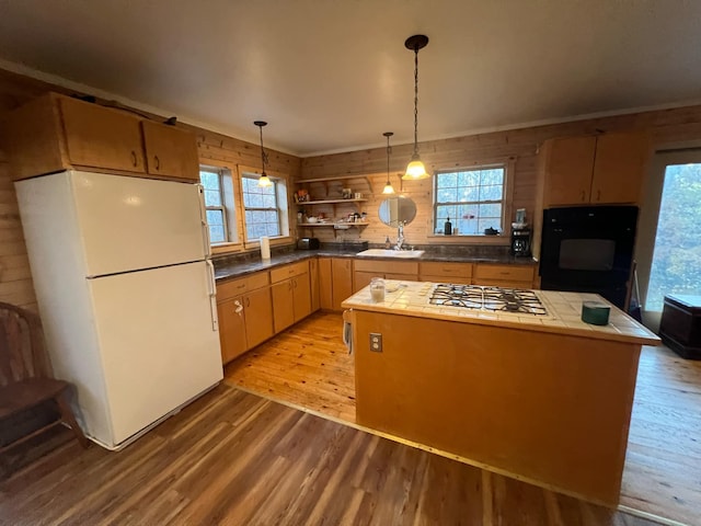 kitchen with decorative light fixtures, light wood-style flooring, a kitchen island, a sink, and white appliances