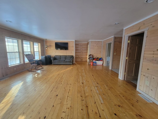 living room with wooden walls, visible vents, and hardwood / wood-style floors