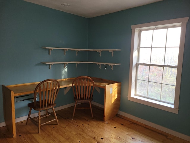 home office featuring built in desk, baseboards, and hardwood / wood-style floors