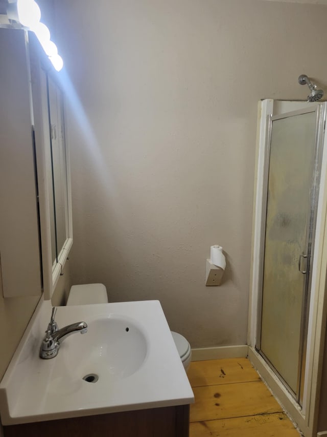 full bathroom with baseboards, toilet, wood finished floors, vanity, and a shower stall