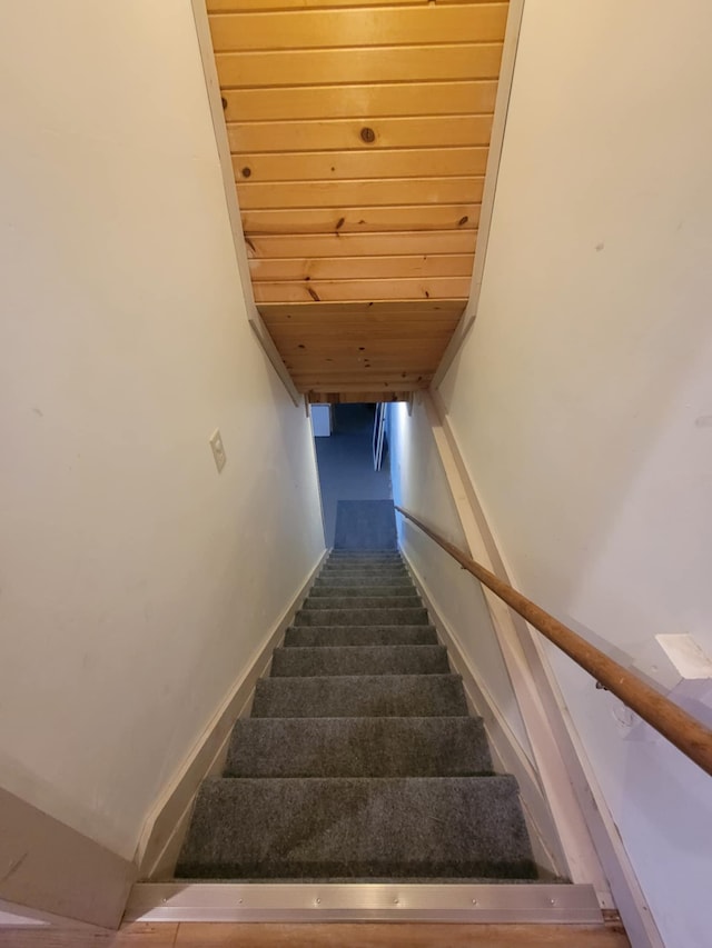 stairs with carpet floors, wood ceiling, and baseboards