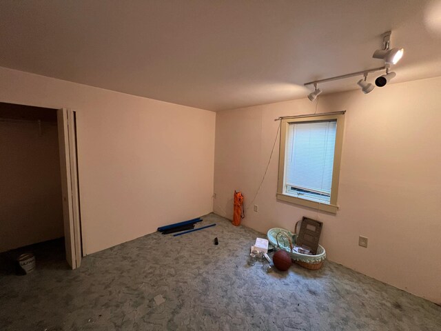 unfurnished bedroom featuring carpet and rail lighting