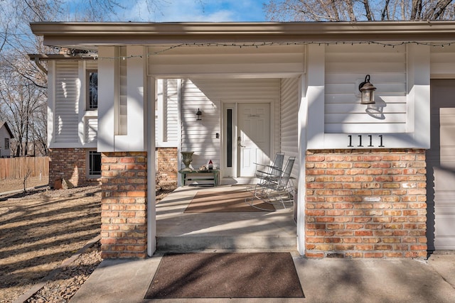 entrance to property with brick siding and a porch