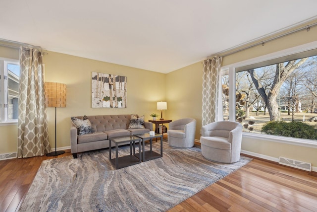 living area featuring baseboards, visible vents, and hardwood / wood-style floors