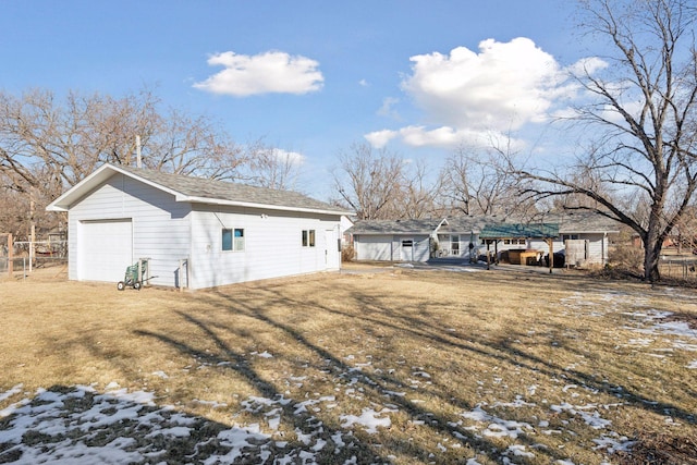 snow covered property featuring a garage, an outbuilding, and a lawn