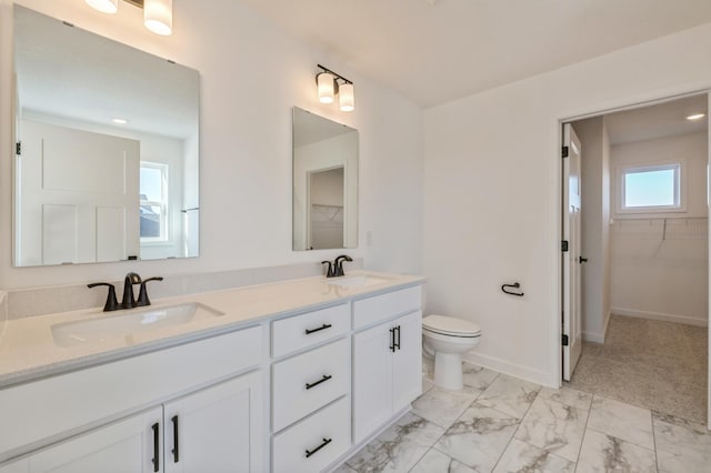 bathroom featuring marble finish floor, a sink, a spacious closet, and double vanity