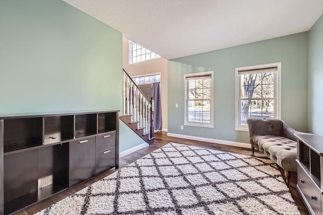 living area with dark wood-style floors, baseboards, and stairway