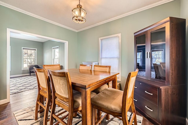 dining room featuring hardwood / wood-style flooring, baseboards, ornamental molding, and an inviting chandelier